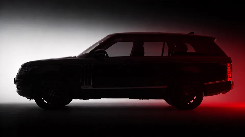 Stately luxury SUV in side-profile silhouette, body edges catching dark red light